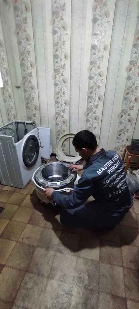 Мастер ремонтирует разобранную стиральную машину